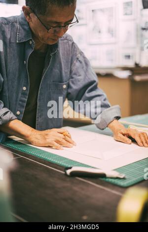 Senior craftsman examining paper while working in shop Stock Photo