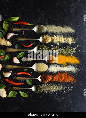 Composition of small spoons full of spices and condiments for cooking on a  black background Stock Photo - Alamy