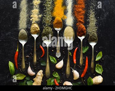 Composition of small spoons full of spices and condiments for cooking on a  black background Stock Photo - Alamy