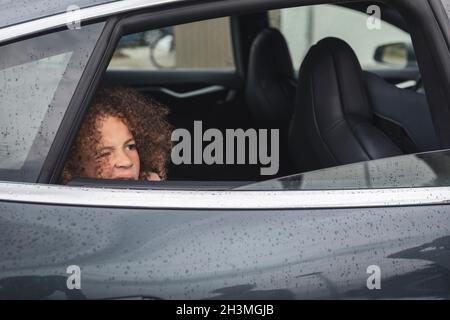 Girl looking through window of car Stock Photo