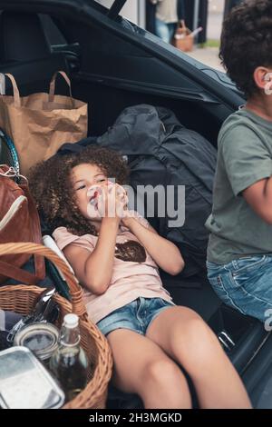 High angle view of girl eating apple by brother in car trunk Stock Photo