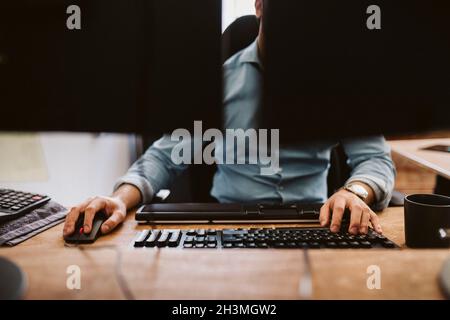 Businessman using computer while sitting at desk in office Stock Photo