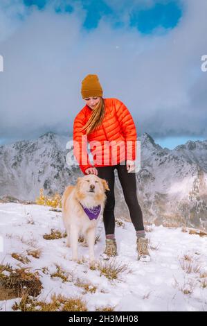 Female Hiker and Fluffy Dog on A Snowy Mountain Ridge Stock Photo