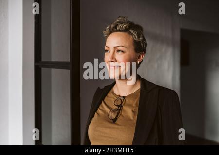 Smiling mature businesswoman standing while looking away Stock Photo