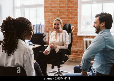 Female and male professionals laughing while discussing in office Stock Photo