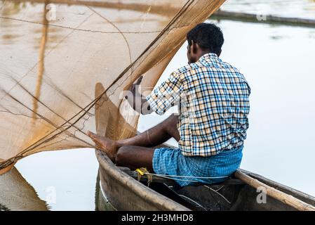 Fisherman repairing chinese fishing net hi-res stock photography