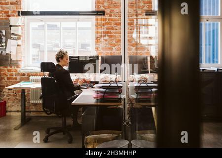 Female manager using laptop while sitting at desk in creative office Stock Photo