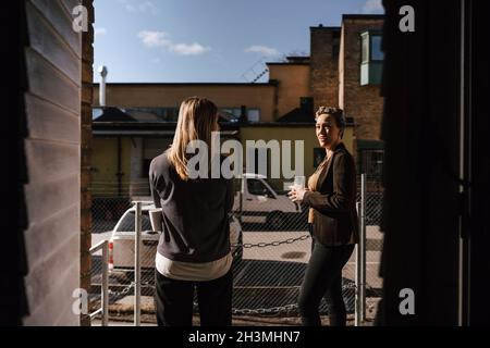 Female business colleagues talking outside office Stock Photo
