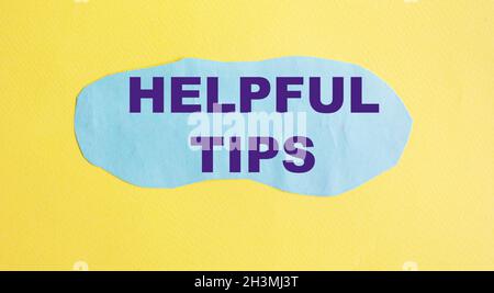 Helpful tips text is written on a blue piece of paper, on a yellow background. Stock Photo