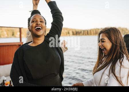 Cheerful woman dancing with female friends during party in evening Stock Photo