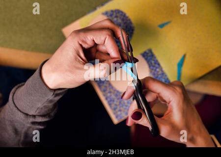 scissors in female hands close-up. top view of the process of cutting paper with scissors Stock Photo
