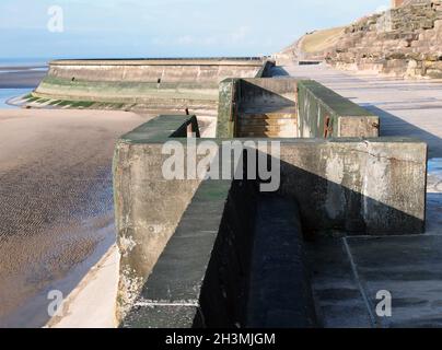 Concrete stairs on seawall in blackpool with the beach at low tide in sunlight Stock Photo