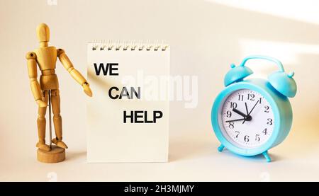 We can help, text on a notebook and a wooden doll and a clock on a white background Stock Photo