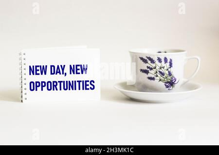 NEW DAY, NEW OPPORTUNITIES,the text is written in a notebook and on a white background with a tea cup Stock Photo