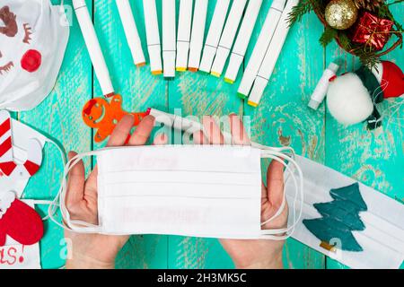 Celebrating Christmas amid a pandemic. We draw pictures and inscriptions on medical masks. Children's art project Stock Photo