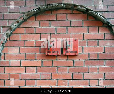 Two old red metal fire switches on an exterior brick wall Stock Photo