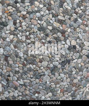 Multi-colored sea pebbles at pathway outdoors. Small round stones are in cement mortar. Selective focus at centre of image. Abst Stock Photo