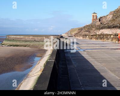 Concrete stairs on seawall in blackpool with the beach at low tide in sunlight with the old boat pool and tower in the differenc Stock Photo