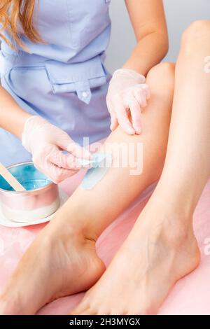 Sugar and waxing depilation of the feet in the beauty salon. Rid of hair on the legs. Sugaring. Master cosmetologist removing ha