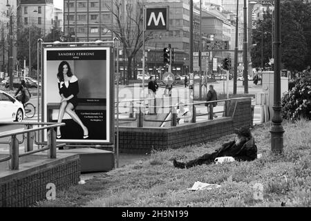 Milan, Italy; March 23th 2011: Homeless man lying next to a luxury goods advertisement. Stock Photo