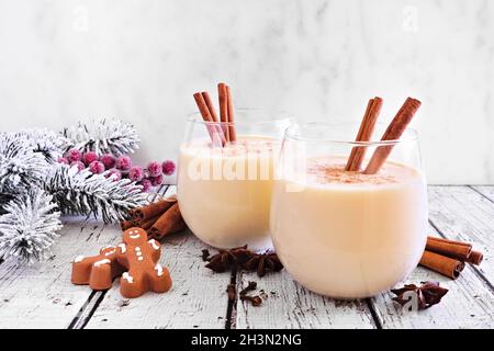 Spiced Christmas eggnog with gingerbread men and holiday decor against a white background Stock Photo