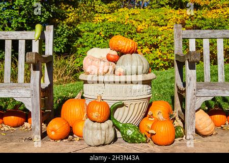 Planter filled with pumpkins and gourds for fall between two benches Stock Photo