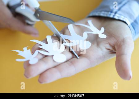 Woman cuts paper figures of family with scissors closeup Stock Photo