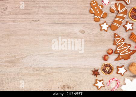 Christmas gingerbread cookies, candy and baking items. Overhead view side border on a wood background. Stock Photo