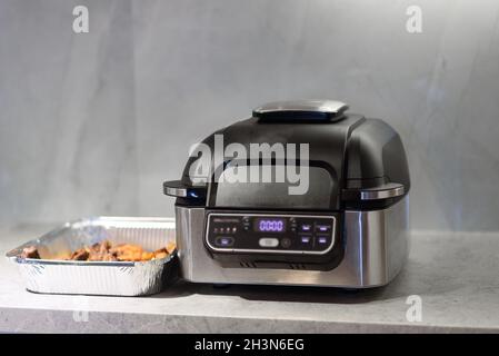 Air fryer in kitchen. Cooking meat with spices in an air fryer. Selective focus on airfryer. Stock Photo