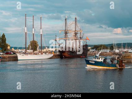 Honfleur, France - July 28, 2021: Fishing boat leaving the historical port of Honfleur in Normandy with two spanish galleys Stock Photo