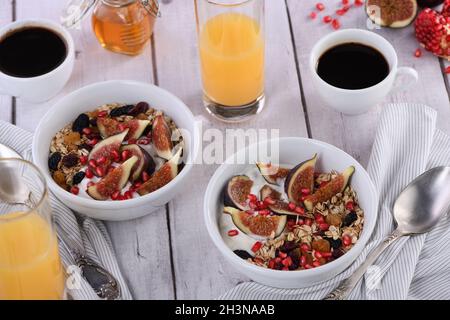 Healthy and delicious breakfast. Oatmeal muesli with Greek yogurt, fresh figs, dried fruits and pome Stock Photo