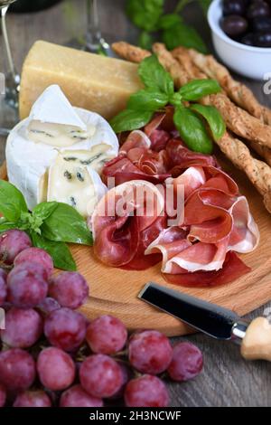 Antipasto. Wine set snacks of dried ham, brie cheese with mold, parmesan with grissini, olives and p Stock Photo