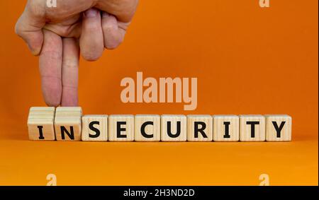 Security or insecurity symbol. Businessman turns wooden cubes, changes words insecurity to security. Beautiful orange background. Business, security o Stock Photo