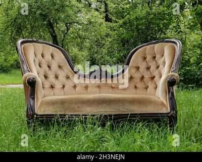 Luxury vintage sofa at green grass in the garden. Spring time. Front view Stock Photo