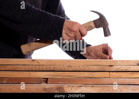 Man hammering nails into wood, isolated on white background. Unknown man in carpentry work. Stock Photo