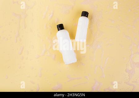 Two plastic bottles of different size on light yellow. No label. Close up, top view, copy space for text or logo. Stock Photo