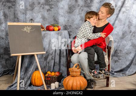 boy holding a basket with autumn harvest of nuts, red apples on the table, autumn season, autumn 2021 Stock Photo