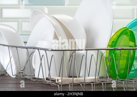 Dish rack with clean dry dishes on kitchen counter Stock Photo
