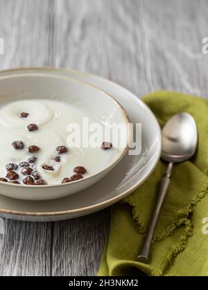 Dry breakfast. Milk splashing into a bowl with chocolate cornballs. A bowl of chocolate flakes on the table. Selective focus Stock Photo