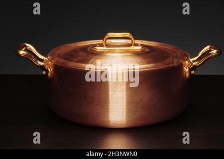Shiny vintage copper cookware over dark background Stock Photo