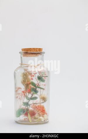 Bouquet of dry flowers and potpourri in a glass jar on a white table Stock Photo