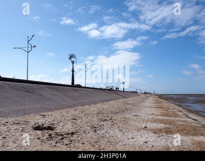 The seafront promenade in southport viewed from the beach with people walking along the promenade and decorative street lamps Stock Photo