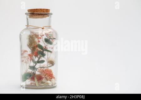 Bouquet of dry flowers and potpourri in a glass jar on a white table Stock Photo