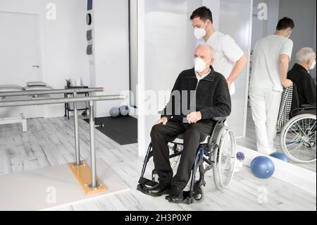 Male Nurse assisting a senior handicapped patient in wheelchair at rehabilitation center. Stock Photo