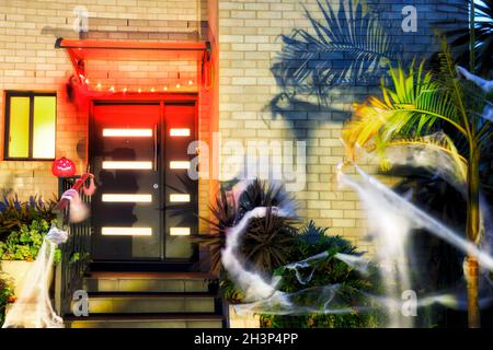 Entrance to a residential house decorated for Halloween with lights, webs, spiders, pumpkin and ghosts. Stock Photo