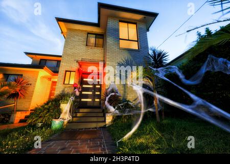 Facade of Halloween decorated house in Australia - green front yard and spider webs everywhere with lights. Stock Photo