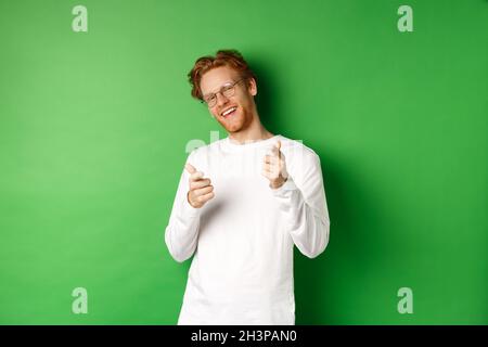 Cheeky young man in glasses praising and congratulating you, pointing fingers at camera and smiling, standing in glasses and whi Stock Photo