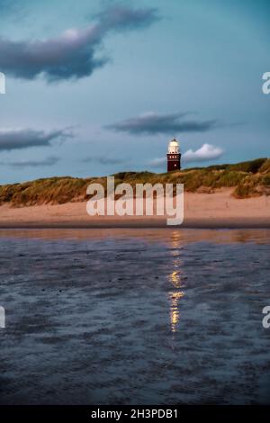 Lighthouse standing on the Dutch coast with a dramatic. and colorful dusk or dawn sky behind it Stock Photo