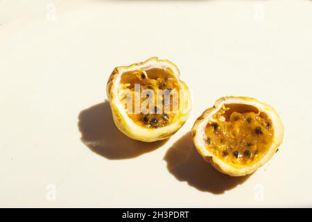 Yellow passion fruit or Passiflora edulis sliced in half against a white background Stock Photo
