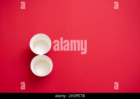 Two empty paper cups in the shape of the number 8. On a red background. Copy space for text Stock Photo